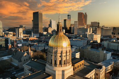 Morning sun on the gold dome of the Georgia State Capitol building with the Atlanta, Georgia skyline in the background.