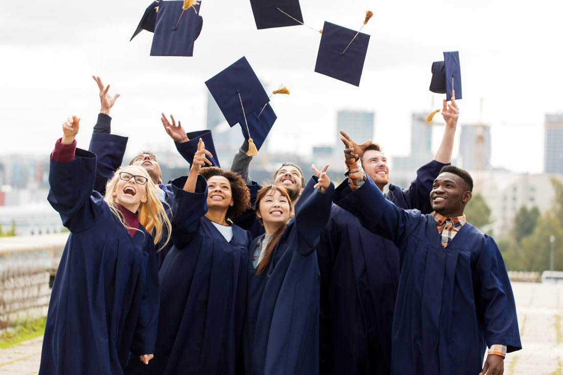 college graduates throwing caps after commencement