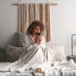 woman starts her day drinking coffee in bed