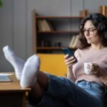 woman succumbing to procrastination by looking at phone