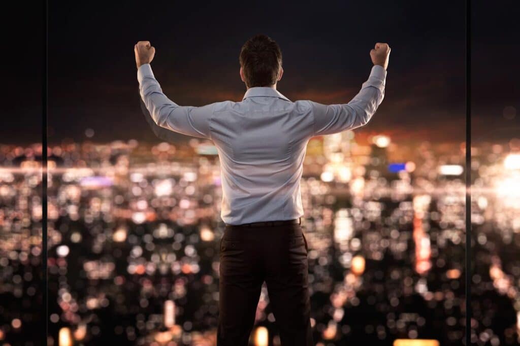 triumphant man looks out over a city skyline inspiring greatness