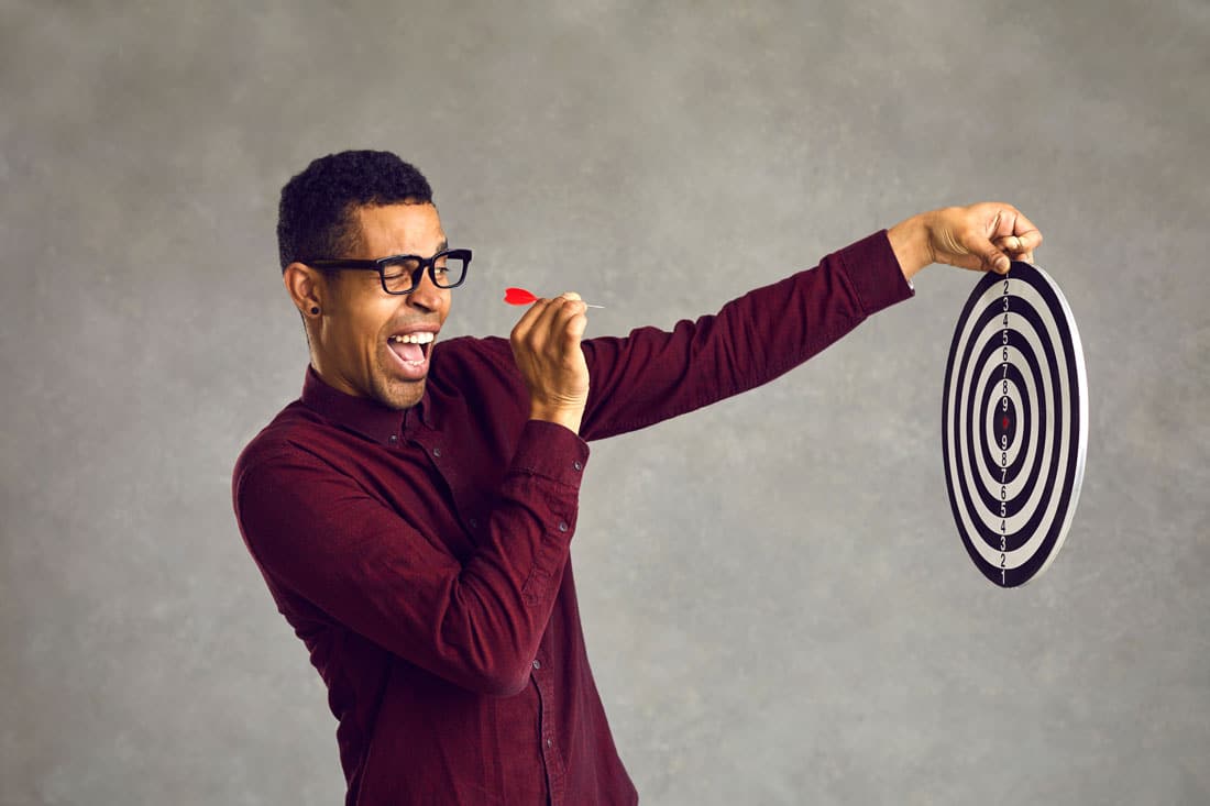 Young man aims for the bullseye exemplifying quotes about achieving goals