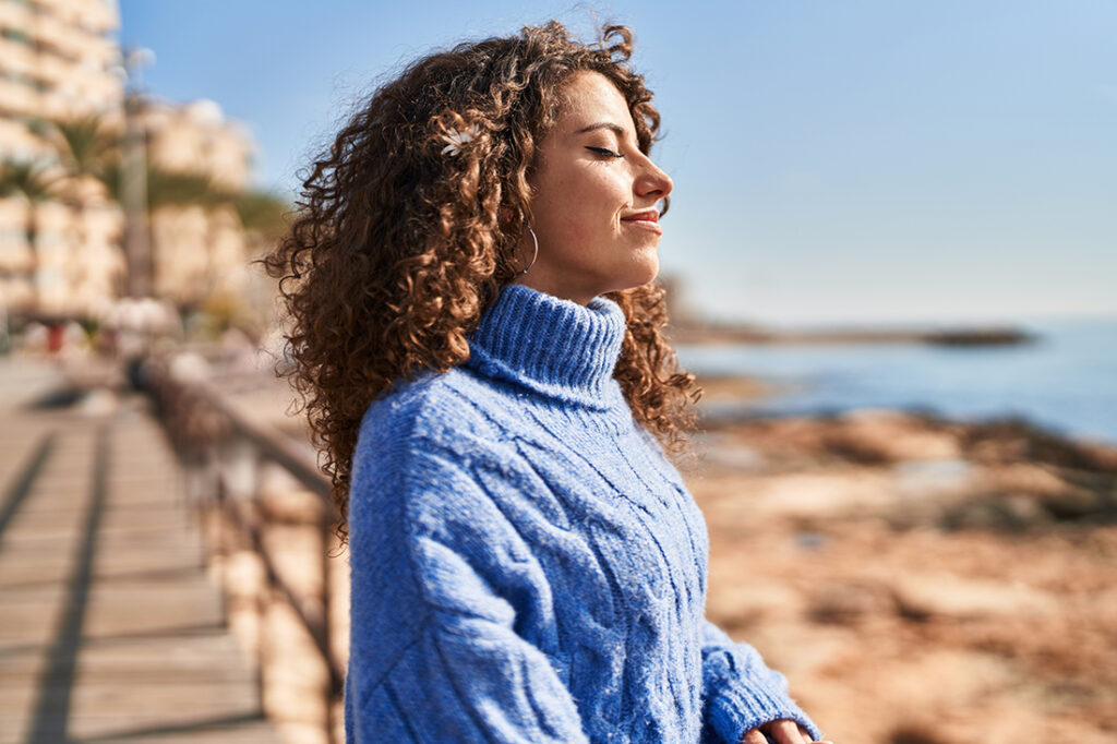 Young hispanic woman in blue sweater smiling