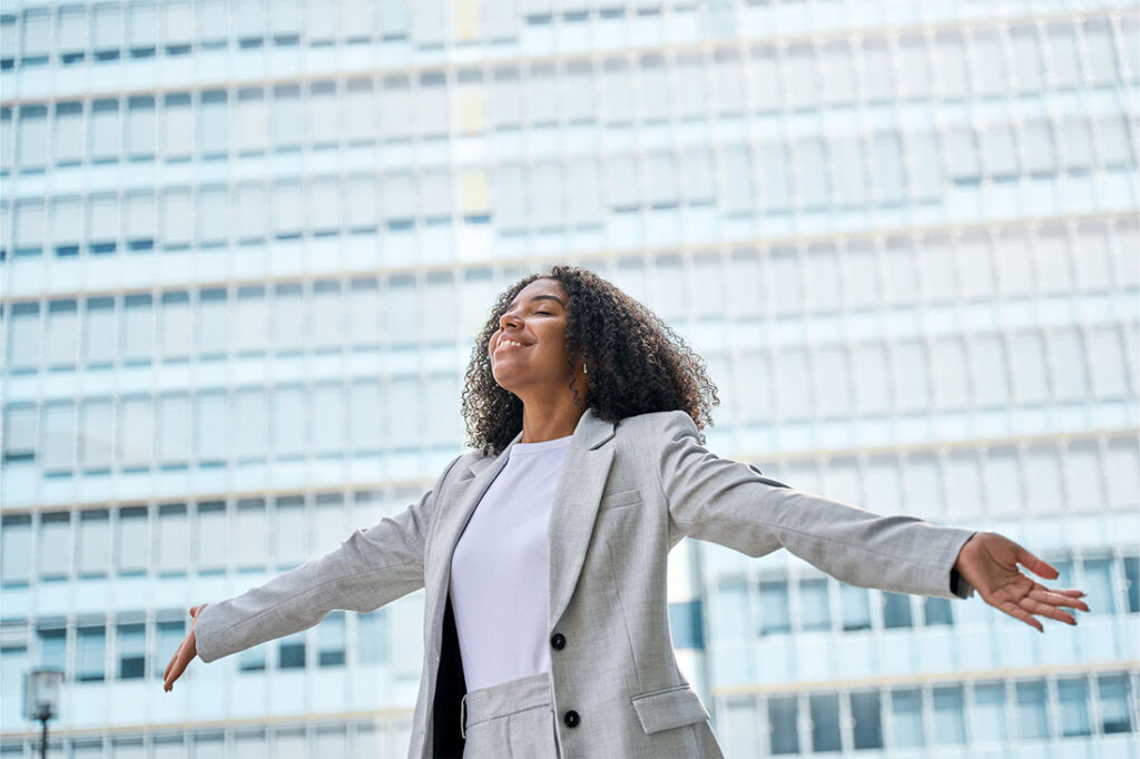 Confident professional young African American business woman wearing suit outstretching arms