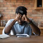 man sitting at a table with head in his hands dwelling on negative mental filters