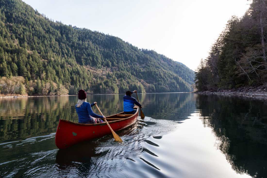 Adventurous couple canoe through a lake contemplating quotes about freedom