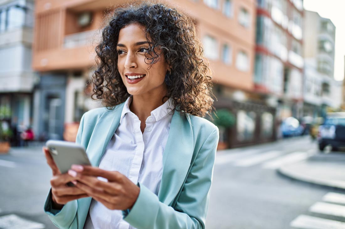 Hispanic businesswoman on her phone on the city showing her characteristics of time management