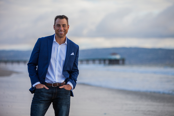 Ricky Mendez smiling on the beach in a suit because he is teaching kids gratitude