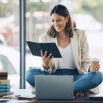 Business woman reading books about setting goals, sitting on her desk drinking coffee