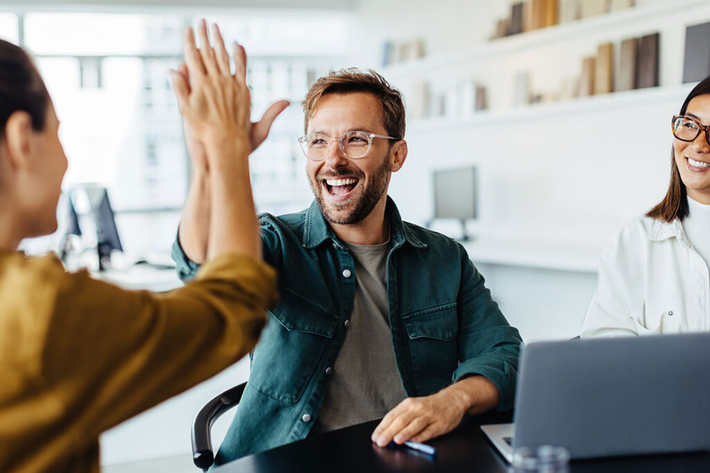 Successful business people giving each other a high five in a meeting