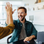 Successful business people giving each other a high five in a meeting