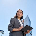 Young Asian business woman planning her time management strategies on a tablet outside in the city