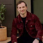 Airbnb co-founder Joe Gebbia sitting on a doorstep smiling at the camera