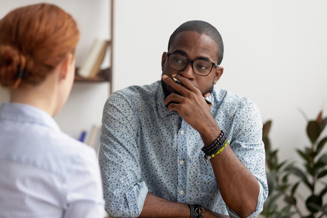 woman holding a money conversation in the workplace with a middle-aged man who looks concerned and has his hand across the bottom half of his face