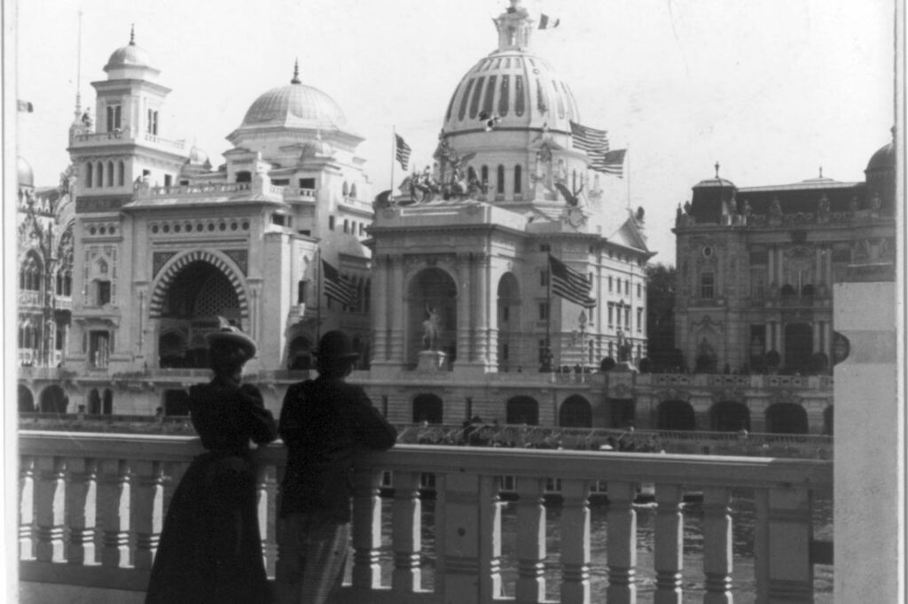 a man and woman look out over a view of Paris during the exposition featuring US manufacturers