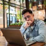 business manager in front of his computer looking frustrated because he's dealing with a toxic client