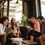 Photograph of 4 people working together and smiling to represent the components of emotional intelligence