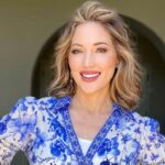 Debbie Biery, a white woman with shoulder length blond hair, red lipstick, and a blue floral shirt, smiling to represent her CEO mindset