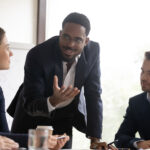 Photograph of a Black man leading his colleagues through a presentation, speaking with his hands to demonstrate emotional intelligence in leadership