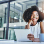 Young Black woman doing a personal development course and smiling in business attire.