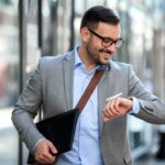 Businessman walking in the city and looking at his watch because he understands the importance of time management