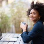 Black woman working outside on her personal development plan and drinking coffee