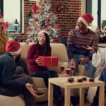 5 colleagues in Santa Claus hats exchanging Christmas gifts for coworkers