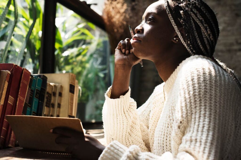 Thoughtful Black woman writing in her gratitude journal