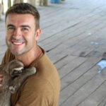 Man holding a sloth and smiling at a volunteer abroad program