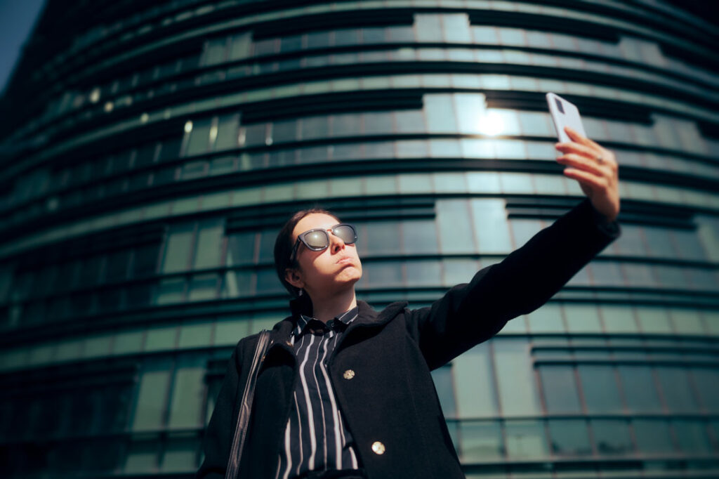 Woman taking with main character syndrome taking a selfie in front of the office