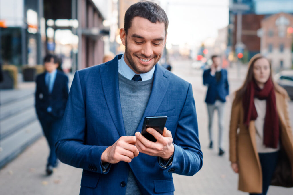 Businessman smiling at looking at the goal setting app on his phone