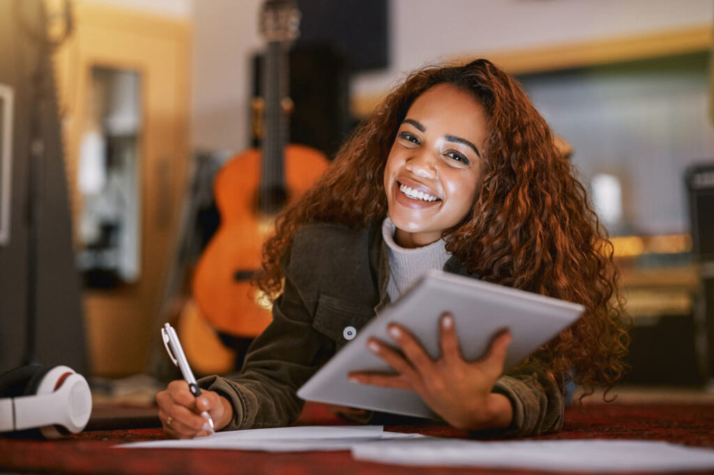 Woman writing down her goals and smiling because she knows the importance of goal setting
