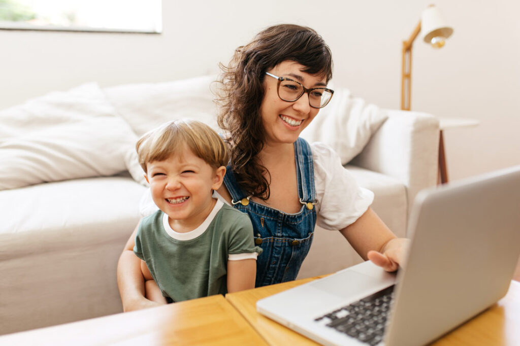 Woman working from home with her son on her lap because her job has support for working parents in the workplace