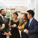 group of men and women holding coffee and engaging in small talk