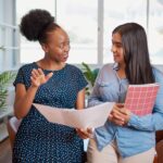 Two businesswomen talking at work learning what a mentor does