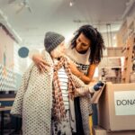 Volunteer putting a jacket on an elderly woman in need learning how volunteering helps mental health