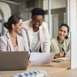 three women looking at laptops