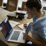 Woman in blue sweater studying at computer