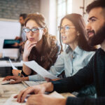 Three business professionals gathered around a computer