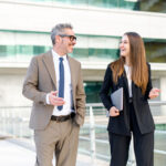 Older male mentor and younger female mentee walking and talking