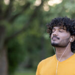 young man with dark hair wearing yellow shirt taking a deep breath