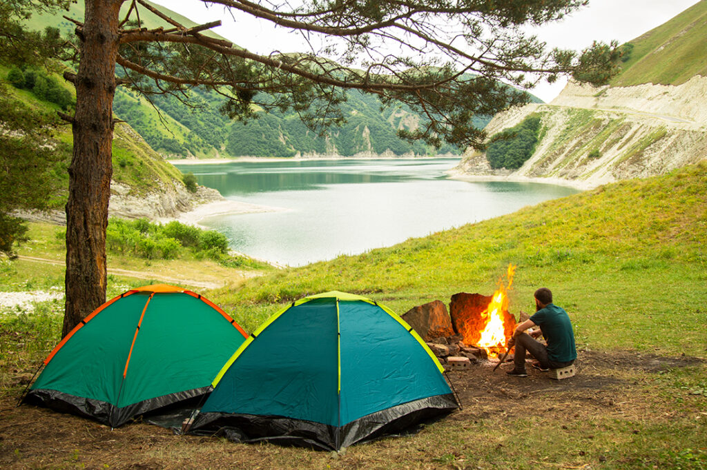 Person sitting by campfire next to tents