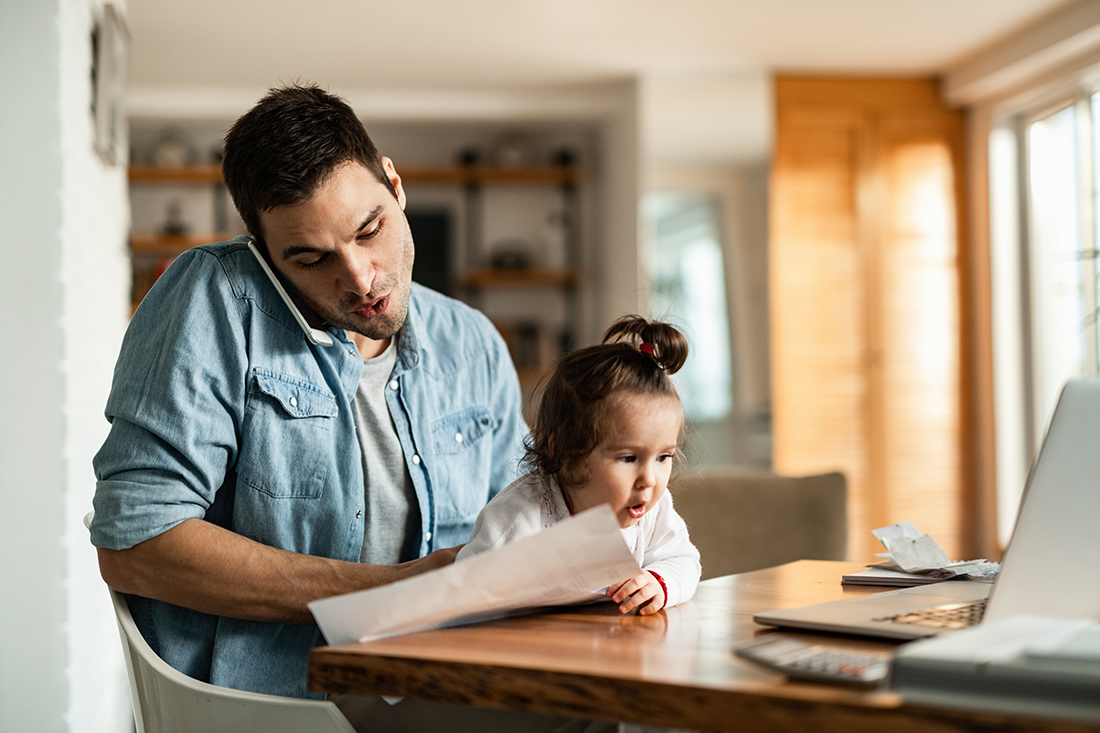 dad working on phone while holding young child