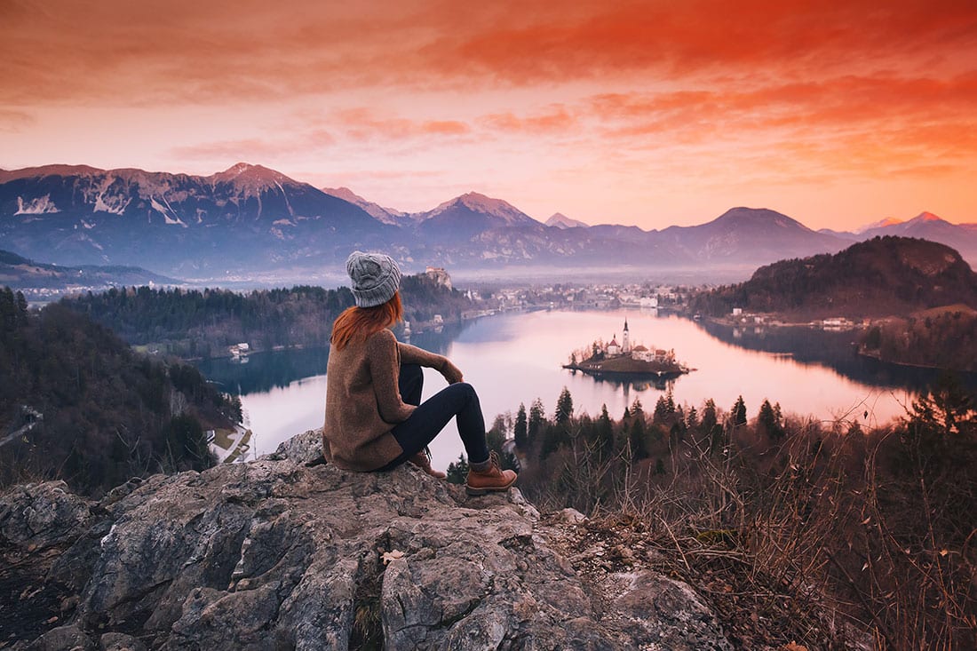 Woman looking on Lake Bled with Island, Castle and Alps Mountain in background.