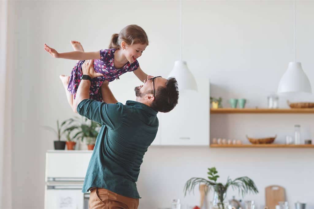 man holding daughter up in air playfully