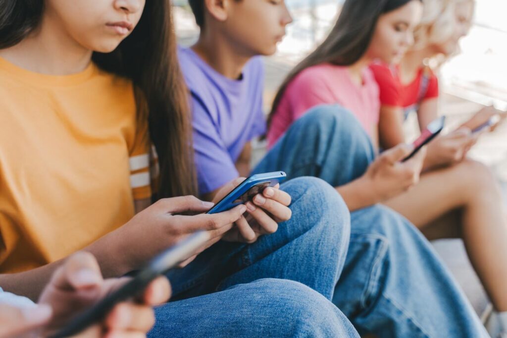 Group of children staring at their phones. Should social media be regulated? surgeon general warning social media