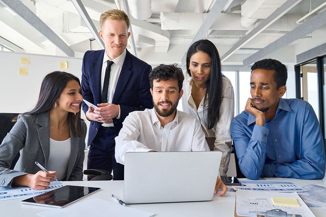 Diverse group of professionals looking at laptop in office