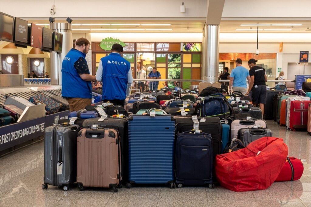 Delta Airlines associates stand in front of rows of lost luggage during the 2024 Crowdstrike Global IT Outage