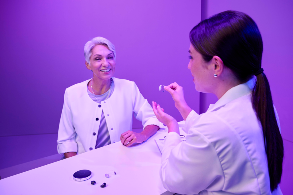 An audiologist shows a Starkey hearing aid to a patient.