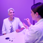 An audiologist shows a Starkey hearing aid to a patient.